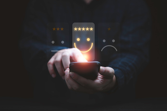 Businessman using smartphone for select smiley face icon for client evaluation and customer satisfaction after use product and service concept.